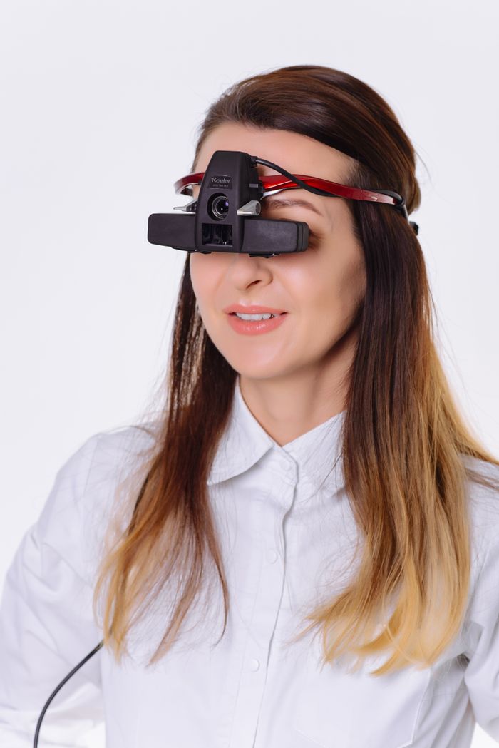 services-04 Woman wearing eye examination equipment in a clinical setting. Modern optometry technology.