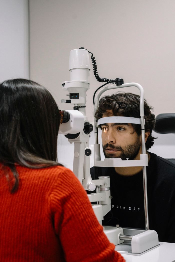 services-01 A man undergoes an eye examination using specialized equipment in a medical clinic.
